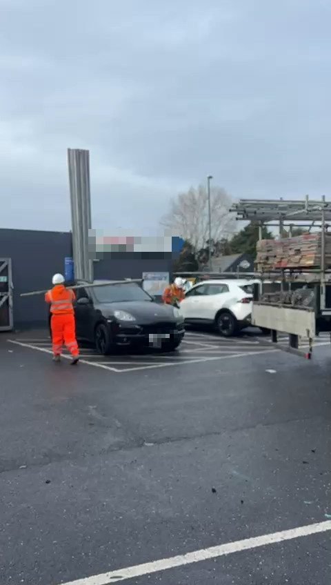 HTK scaffolders unloading scaffold tubes in a retail car park, with the store behind